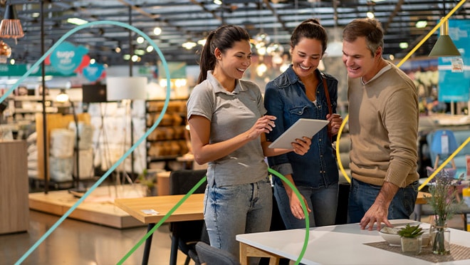 Three people standing in a retail store looking at a tablet computer. 