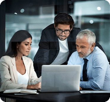 Three people looking at a laptop computer at a desk